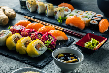 Sushi Set sashimi and sushi rolls served on stone slate