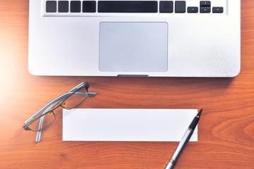 Laptop with blank white label and pen on wooden table