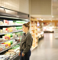Woman  shopping in supermarket, reading product information