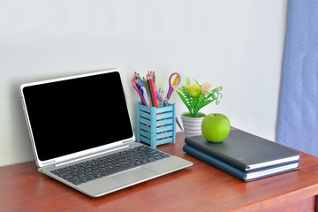 Fototapeta na wymiar Office supplies, laptop with notebook and apple on wooden table