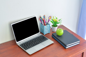 Office supplies, laptop with notebook and apple on wooden table