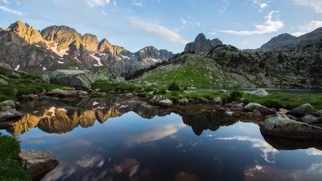 Breathtaking sunrise captured in timelapse, highlighting the reflections and dynamic sky changes over Posets Maladeta Nature Park in the Pyrenees, Spain