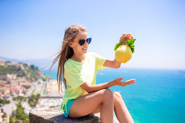 Big yellow lemon in hand in background of mediterranean sea and sky.