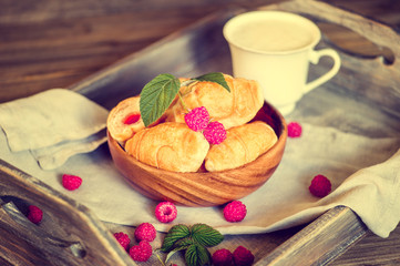 Croissants with raspberries on a wooden tray. The concept of a wholesome breakfast.