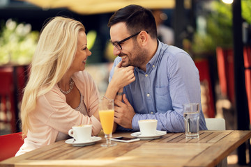 Happy couple showing affection while being on a date in a cafe.