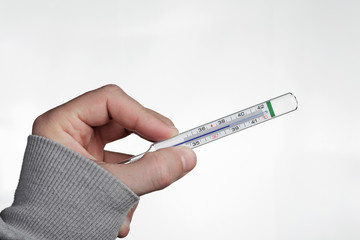 A hand holding a medical thermometer showing a high temperature.