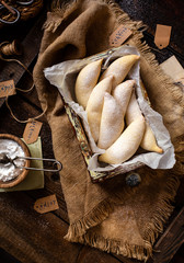 overhead shot of homemade banana shaped cookies in wooden basket on rustic brown table