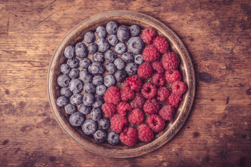 Delicious ripe blueberry and raspberry berries as a symbol of yin and yang in a metal plate on a...