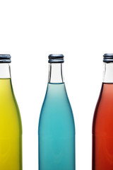 three colorful glass bottles with lemonade on white background. blue bottle whole yellow bottle and red bottle half in the frame