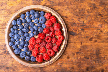 Delicious ripe blueberry and raspberry berries as a symbol of yin and yang in a metal plate on a...