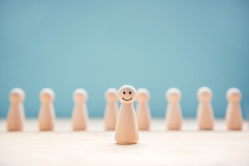 Happy wood people symbol standing out from the crowd.