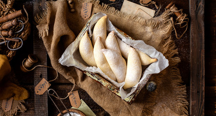 overhead shot of homemade banana shaped cookies in wooden basket on rustic brown table