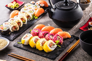 Sushi Set sashimi and sushi rolls served on stone slate