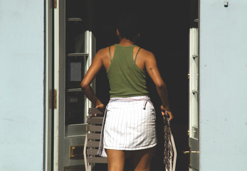 A woman is bringing in foldable chairs into her cafe as it is closing in Edinburgh, Scotland, UK in the summer