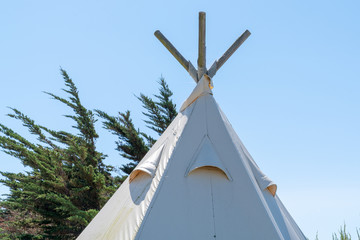 Top of teepee tent against a clear blue sky