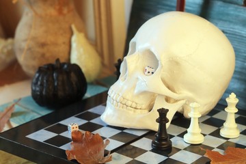  Decorative composition of a skull, pumpkins, frames and mystical decor on a chessboard with figures, on a wooden table, a dark background, interior design for Halloween, autumn, October