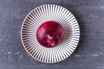 red onion on striped plate from above