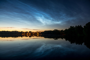 Scenery night sky with silvery clouds (noctilucent clouds) with reflection in water