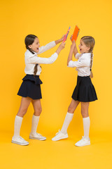 Obraz premium playfool mood. kids learning grammar. back to school. dictionary notebook. Get information. cheerful classmates with workbook. little girls in school uniform. reading story. childrens literature