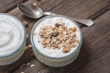 White yogurt in glass bowl with oatmeal on top on rustic wooden desk.