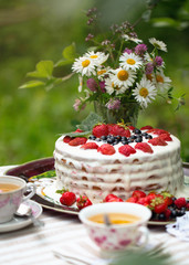 Strawberry cake with cream is on a tray on the table. Tea with a cake. Still life with a strawberry cake and cups of tea.