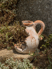Old broken ceramic candlestick on the rock in the garden.