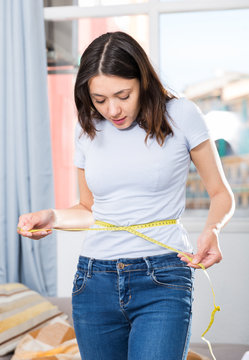 Young girl standing with measuring tape around her waist