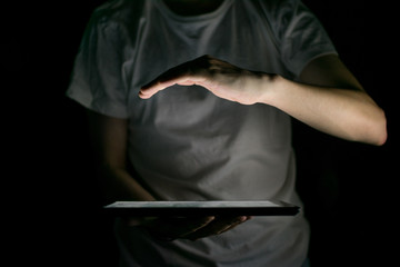 Hand illuminated by the light of a tablet