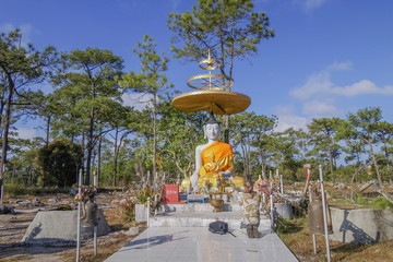 view of Phra Putta Metta Seated Buddha on base around with green forest and blue sky background, Lan, Prasrinakarin mid of trail way, Phu Kradueng National Park, Loei, Thailand.