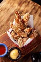 Roasted crunchy chicken strips, made of fillet in breadcrumbs, served with tomato and cheese toppings on a wooden board