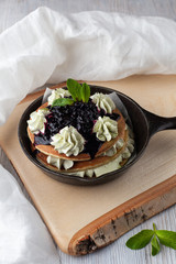 Stack of fluffy pancakes with whipped cream and blueberry sauce, powder with green matcha and...