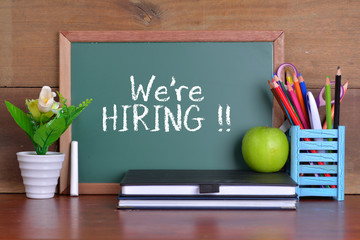 Green school chalkboard with written sentence 'We're hiring'