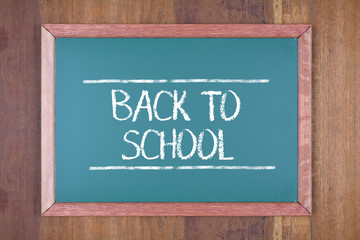 Fototapeta premium Green chalkboard on wooden background with text Back to School