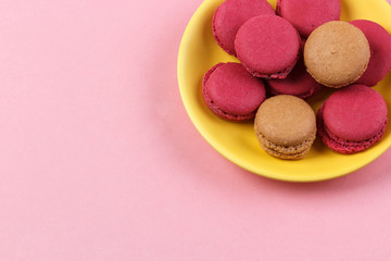 yellow plate with macaroons isolated on pink