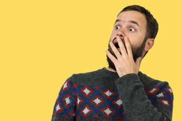 A pensive guy with a beard on a yellow background ponders what to do next. Thinking about question, pensive expression, looks incredulous.