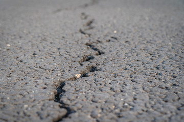 Fototapeta na wymiar terrible crack in the road pavement, close up blurry background