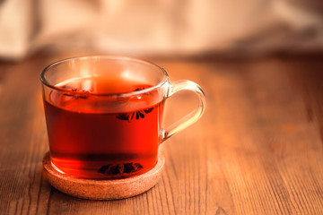a cup of hot black tea with star anise on a wooden table