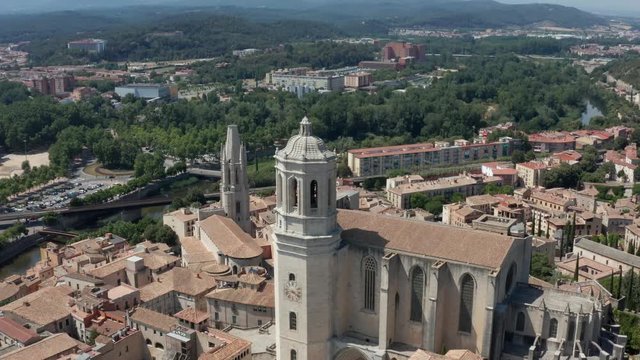 Drone flight over formidable old gothic building, Cathedral of Santa Maria, widest in world, on background of scenic cityscape. Aerial view of medieval quarter on river Onyar, Girona, Catalonia, Spain