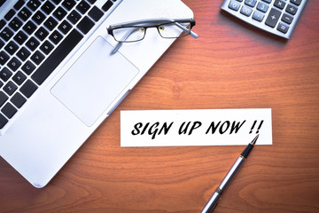 Laptop with glasses, pen and calculator with text SIGN UP NOW