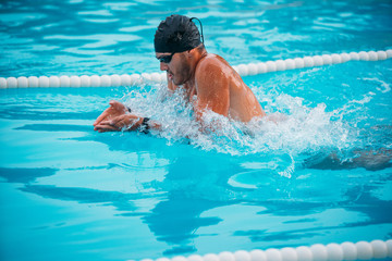 Closeup male athlete swimming breaststroke in pool during Champions.