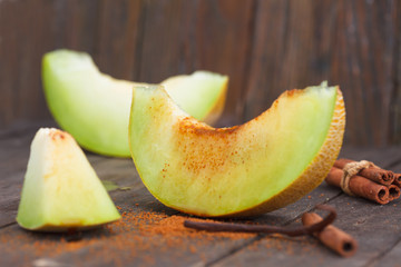 Slices of Cantaloupe melons with cinnemon and brown sugar on woodene background. Refreshing slices of ripe, sweet melon.