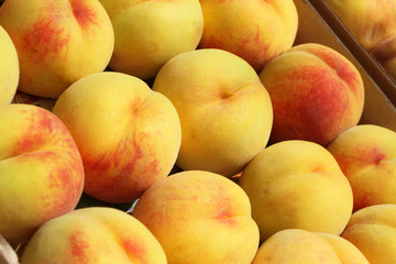 Ripe peaches in a cardboard box on the market. Closeup