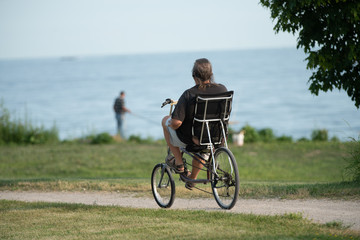 Obraz premium middle aged man rides a recumbent bicycle on a sunny day at the park to keep fit and stay healthy
