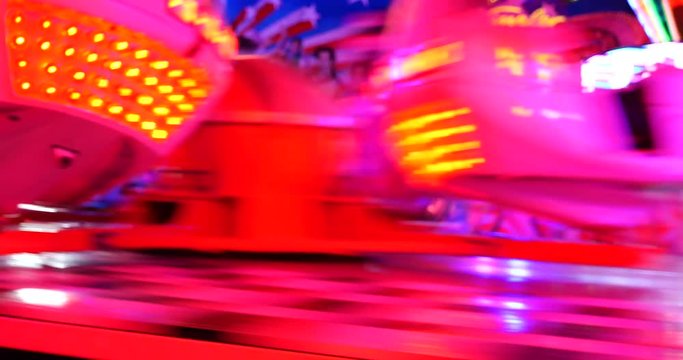 Blur night amusement atmosphere with illuminating red light at "Octopus or Breakdance amusement ride" with speedy movement of rotating sloping platform and spinning seats in D&uuml;sseldorf, Germany.   