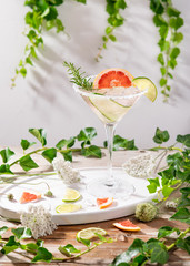 Grapefruit and cucumber, rosemary and lime cocktail, refreshing, cold drinks with ice on a rustic table. Summer garden party, still life with artistic shadows.