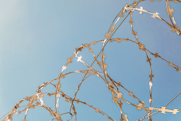 Barbed wire close-up on a blue sky background. Limited depth of field.