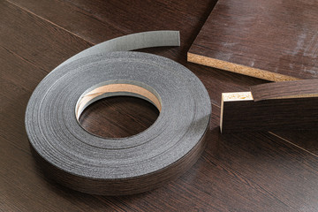 Roll melamine edge for finishing of furniture. Edging tape on laminated chipboard sheets wenge color.