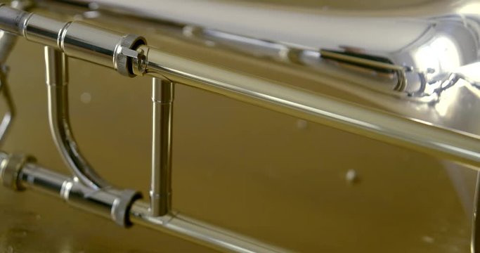 specular metal trombone lies on table reflecting light