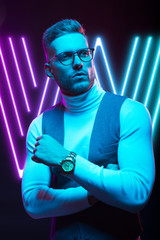 Young handsome model posing in a studio in a trendy neon light. Fashionable man in a stylish suit. Vibrant color. Bright colorful light effects. Disco style. Overlay. Gel filter. Supersaturated