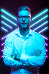 Young handsome model posing in a studio in a trendy neon light. Fashionable man in a stylish suit. Vibrant color. Bright colorful light effects. Disco style. Overlay. Gel filter. Supersaturated
